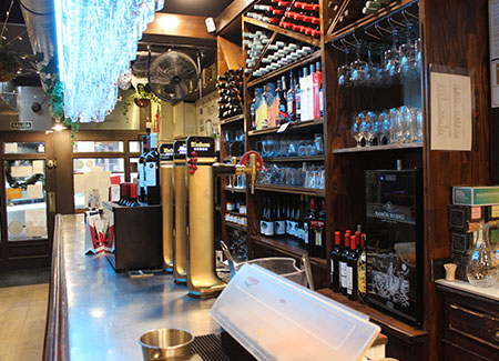 Vista de la barra del bar, dónde podemos ver la barra, con sus cañas de cerveza y la estantería con bebidas y copas