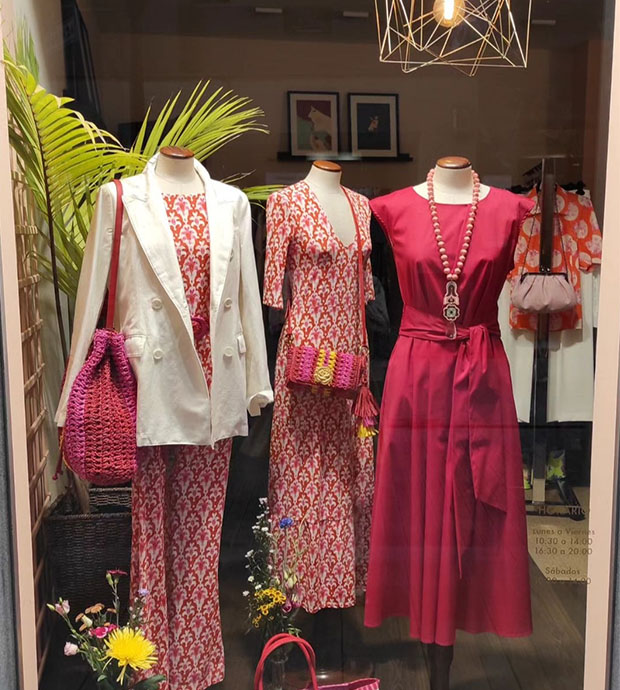 Vista exterior del escaparate, dónde se pueden ver tres maniquís femeninos con vestidos de tonos rojos