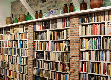 Vista de tres estanterías llenas de libros, separadas por dos columnas de ladrillo que la misma profundidad que las propias estanterías