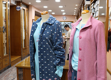 Maniquís femeninos, uno lleva ropa de calle con pijamas de tonos azulados, uno lleva una bata rosa y el otro una bata azul estampada con hojas