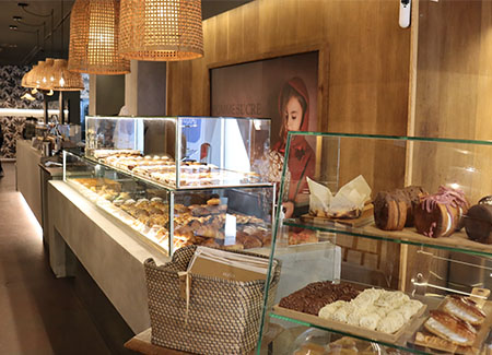 Vista del interior del comercio, dónde se puede ver el gran mostrador expositor lleno de pasteles y otros productos dulces