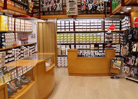 Vista del interior de la zapatería, dónde podemos ver dos mostradores expositores y las paredes cubiertas por estanterías con multitud de cajas de zapatos