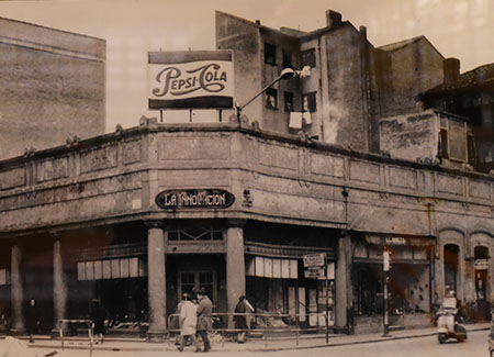 Foto antigua en blanco y negro de la esquina de un edifico con un cartel que pone «La Innvación» bajo un cartel publicitario de «Pepsi-Cola»
