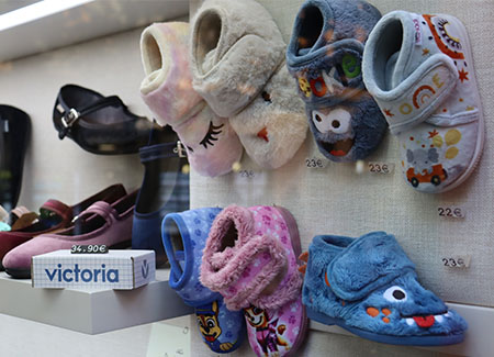 Primer plano de zapatillas infantiles adornadas con ojos, bocas y pestañas expuestas en una pared