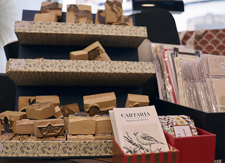 Vista de un expositor con sellos de caucho, frente al expositor vemos unas cajas con material de regalo y de papelería