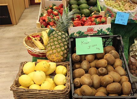 Primer plano del expositor de frutas y verduras, dónde podemos ver frutas de temporada en cestas de mimbre y de madera
